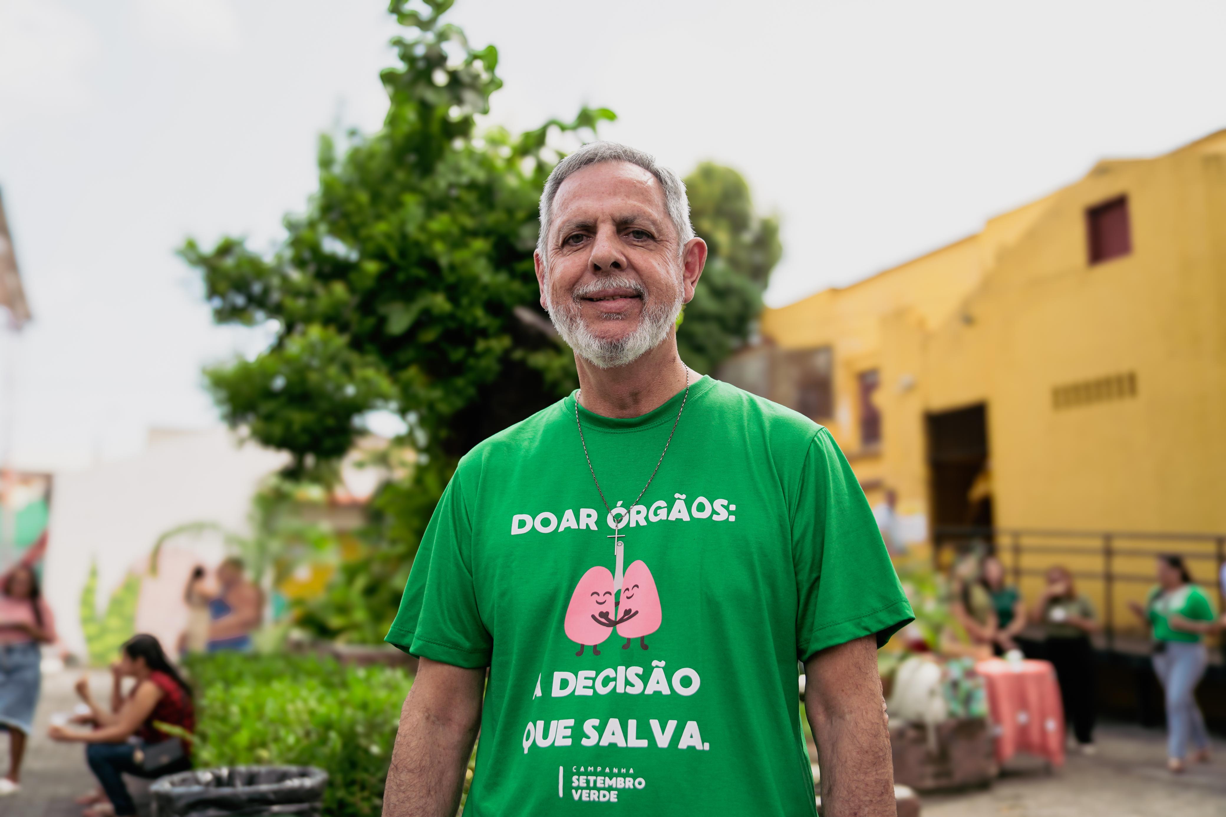 Altair Almeida é um homem branco, com cabelo e barba brancos e veste camiseta verde